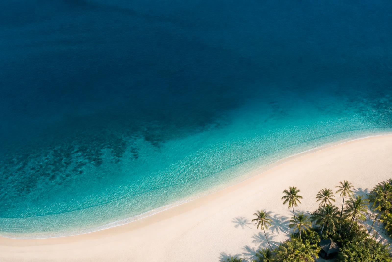 Aerial view of a calm turquoise bay and white sand beach